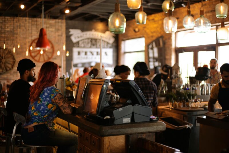 view of a Cafe filled with people engaging in conversations, placing their order, from a counter view