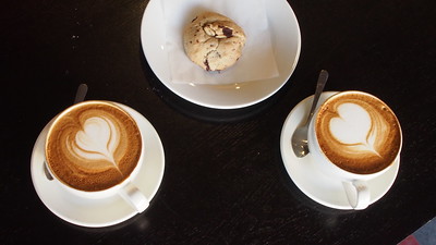 2 cups of sustainable coffee on either side of a vegan baked good