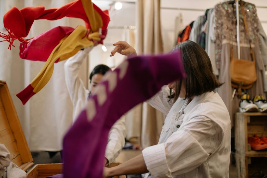 Two female workers handle garments while working inside a store as well as in an upcycle industry space.